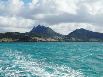 Scenic view of sea by mountains against sky