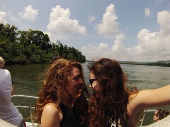 Young women taking selfie in boat at sea against sky