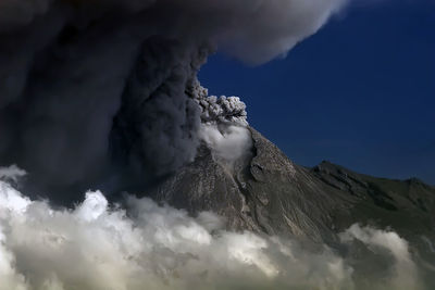 Smoke emitting from volcanic mountain against sky