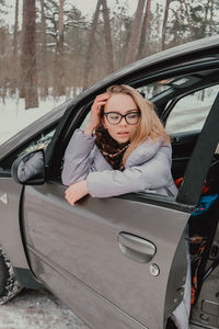 Attractive young female looks out the car window waiting for a trip and smile. winter travel. woman