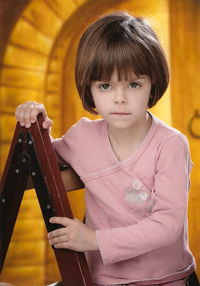 Girl on a wooden ladder with short hair looks directly into the lens