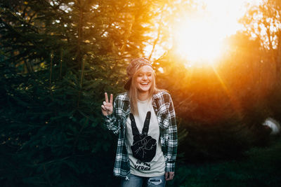 Portrait of smiling young woman standing against tree