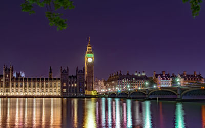 Colorful lights falling by westminster bridge over thames river at night