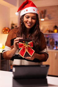 Close-up of smiling woman holding gift at home