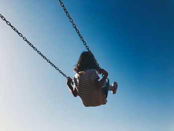 Rear view of girl on swing at playground