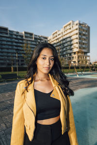 Young woman standing in front of buildings at sunset