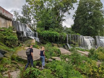 Man and woman standing by plants against trees