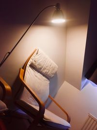 Illuminated electric lamp on bed against wall at home
