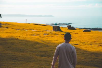 Rear view of man looking at sea against sky