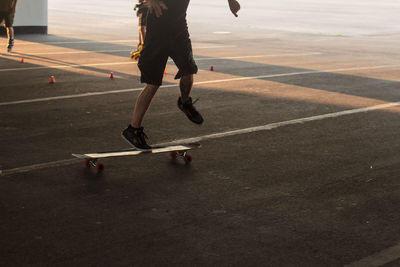 Low section of man skateboarding on road