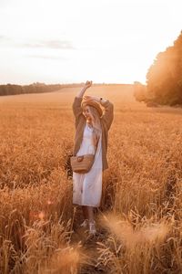 Rear view of woman standing on field against sky