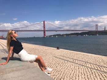 Woman looking at suspension bridge against sky