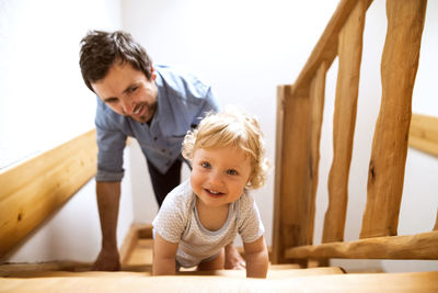 Father with little boy on wooden stairs at home