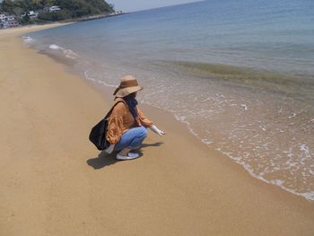 Rear view of woman sitting on beach