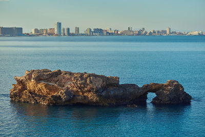 Sea by cityscape against sky