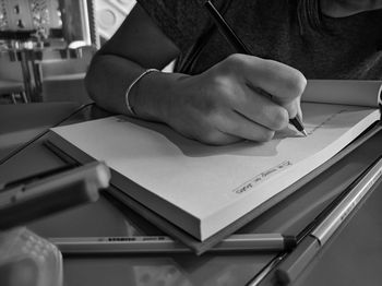 Cropped image of hand holding book on table