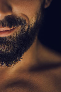 Close-up of man with beard against black background