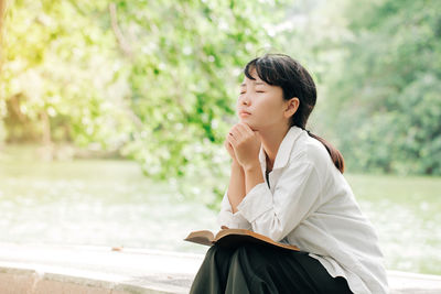 Young woman looking away while sitting outdoors