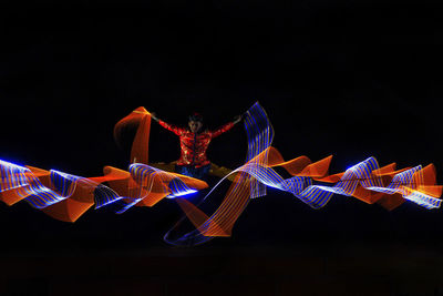 Low angle view of illuminated lighting equipment against black background