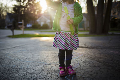 Low section of girl playing with toy while standing on footpath