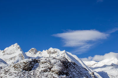 Low angle view of snowcapped mountains against blue sky