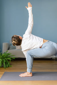 Full length of woman doing yoga at home