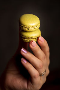 Close-up of woman holding ice cream cone against black background