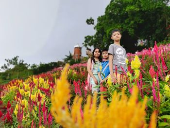 Portrait of smiling young woman standing by flowering plants