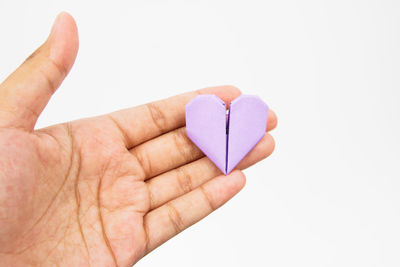 Close-up of hand holding heart shape over white background