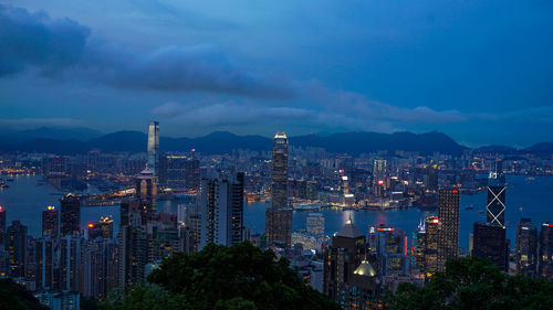 Illuminated buildings in city against cloudy sky