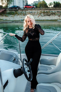 Full length of beautiful young woman in black dress standing in vessel