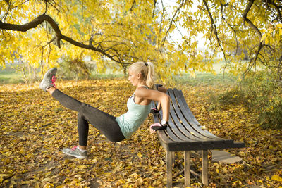 Side view of mid adult woman exercising in park during autumn