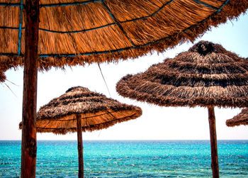 Thatched roof on beach against clear sky