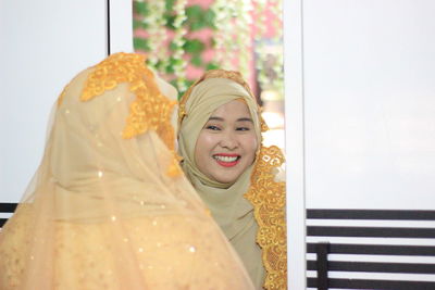 Portrait of smiling young woman seen through glass window