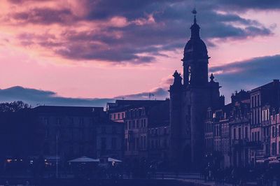 Buildings in city against cloudy sky