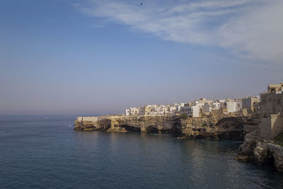 Sea by buildings against sky