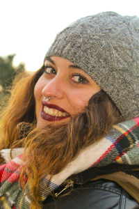 Close-up portrait of smiling young woman against sky during winter