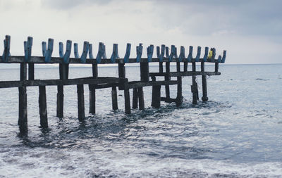 Wooden posts on beach against sky