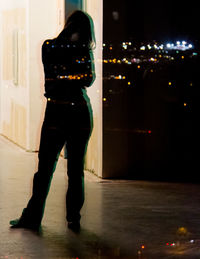 Man photographing woman standing in illuminated city at night