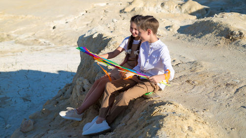 Teenage children with kite rest and communicate with each other.