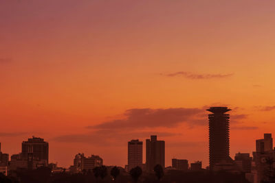 Silhouette buildings against orange sky