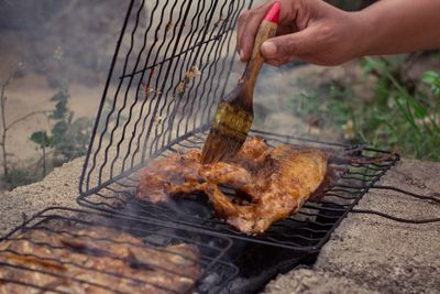 Midsection of person preparing food on barbecue grill