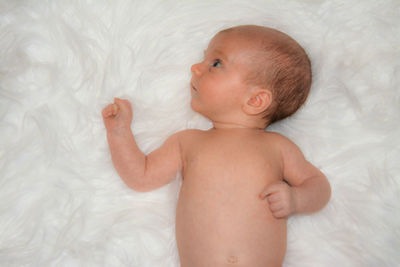 Shirtless baby boy lying on rug