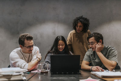 Male and female business colleagues discussing over laptop at conference table in startup company