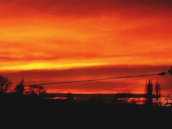 Silhouette landscape against orange sky