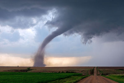 Scenic view of field against storm clouds