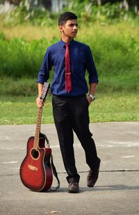 Full length of man with guitar standing on footpath