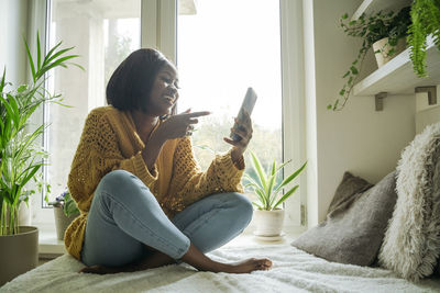 Happy young woman talking on video call through smart phone at home