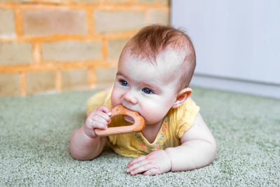 Cute little caucasian baby girl playing with wooden teething toy. eco-friendly toys for kids.