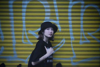 Portrait of woman standing against graffiti shutter